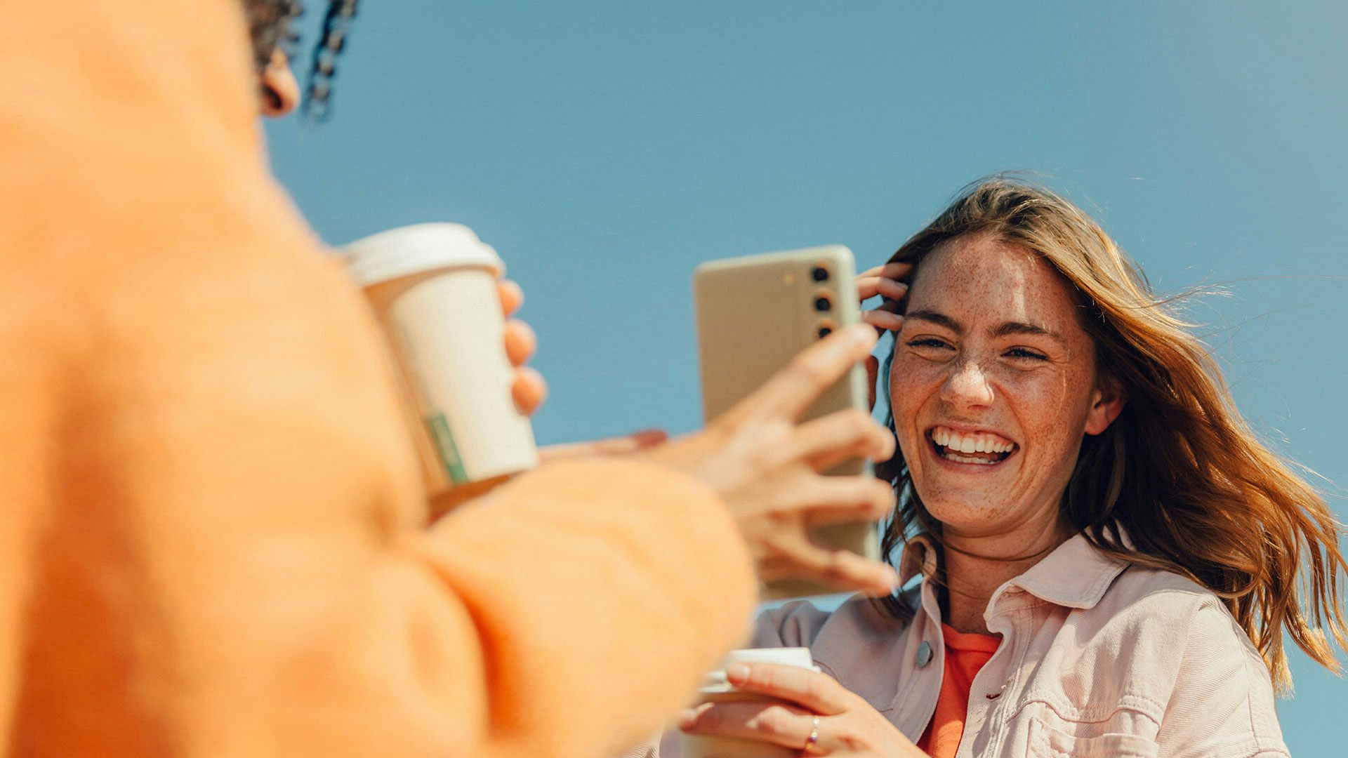 Kompis visar upp sin mobilskärm till kvinna som skrattar